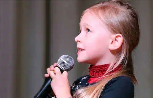 Niña con micrófono: oratoria en las aulas