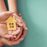 Manos sujetando figura de una casa en papel