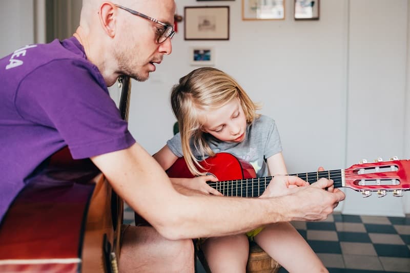 Un Padre Le Enseña A Su Hija A Tocar La Guitarra, Pasando Tiempo En Familia