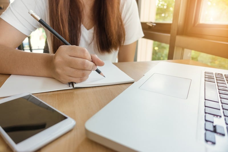 los retos de los examenes online. una alumna toma notas delante del ordenador. 