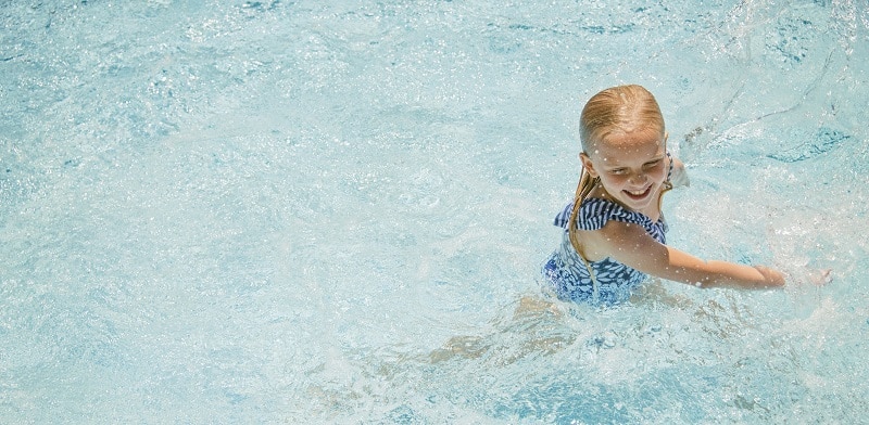 una niña se baña en la piscina en verano - repaso y descanso en vacaciones