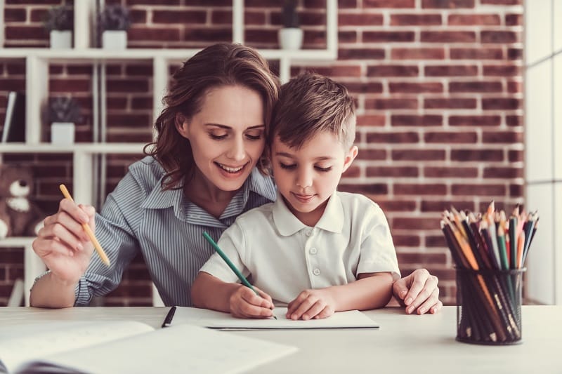 una madre o una profesora ayuda a un niño a hacer la tarea - personas con altas capacidades