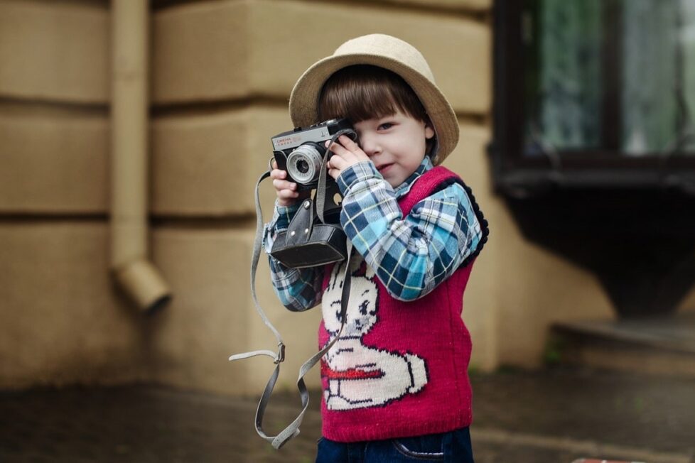 Un niño aprende a usar una cámara de fotos