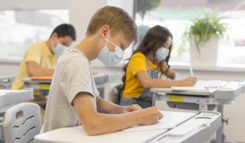 Niños estudiando en clase con mascarilla