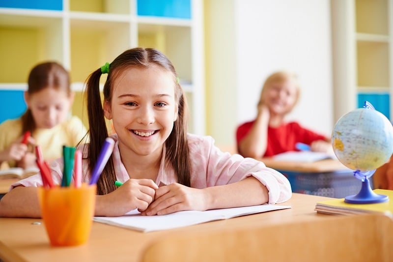 Niños en clase atendiendo a la profesora. 