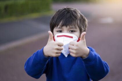 Niño con mascarilla hace el signo de todo ok con los pulgares hacia arriba