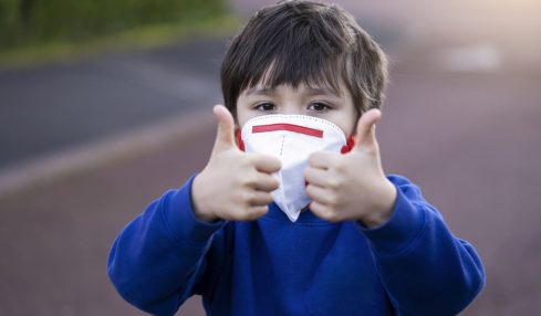 Niño con mascarilla hace el signo de todo ok con los pulgares hacia arriba