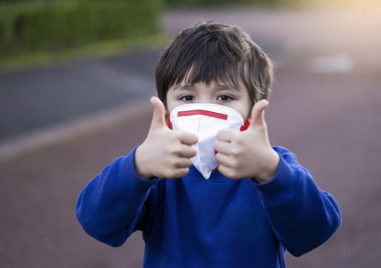 Niño con mascarilla hace el signo de todo ok con los pulgares hacia arriba