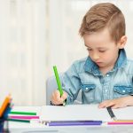 un niño escribe a mano con un lapicero de color verde