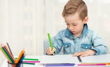 un niño escribe a mano con un lapicero de color verde