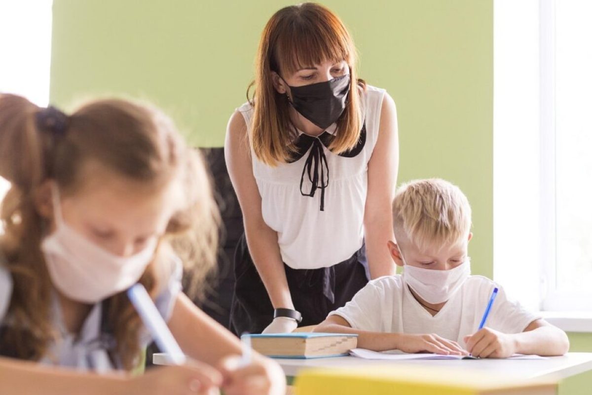 Profesora y alumnos con mascarilla en el aula