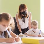 Profesora y alumnos con mascarilla en el aula