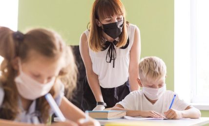 Profesora y alumnos con mascarilla en el aula
