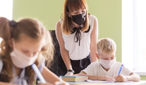 Profesora y alumnos con mascarilla en el aula