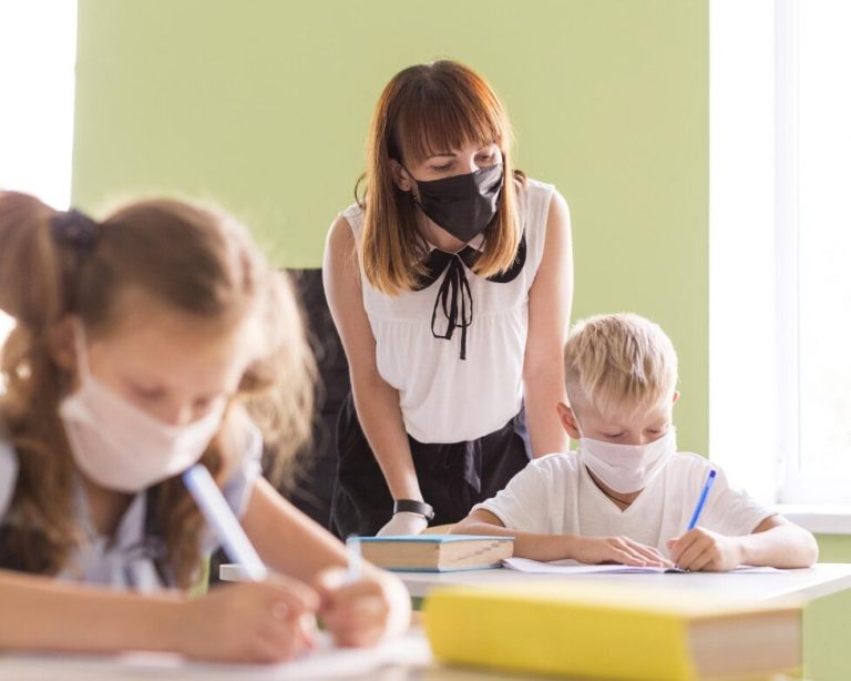 Profesora y alumnos con mascarilla en el aula