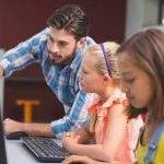 un profesor y sus alumnos usan un ordenador con soluciones de Microsoft centradas en la seguridad