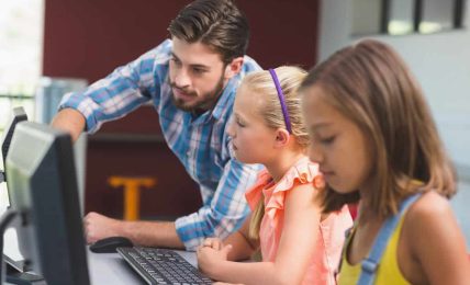 un profesor y sus alumnos usan un ordenador con soluciones de Microsoft centradas en la seguridad