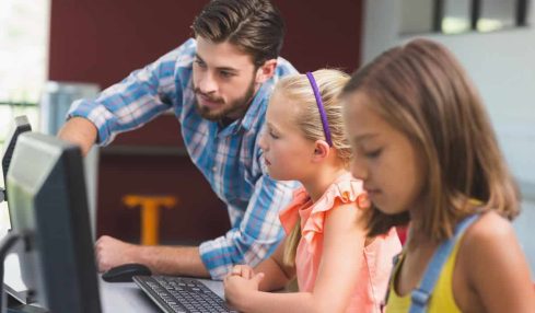 un profesor y sus alumnos usan un ordenador con soluciones de Microsoft centradas en la seguridad