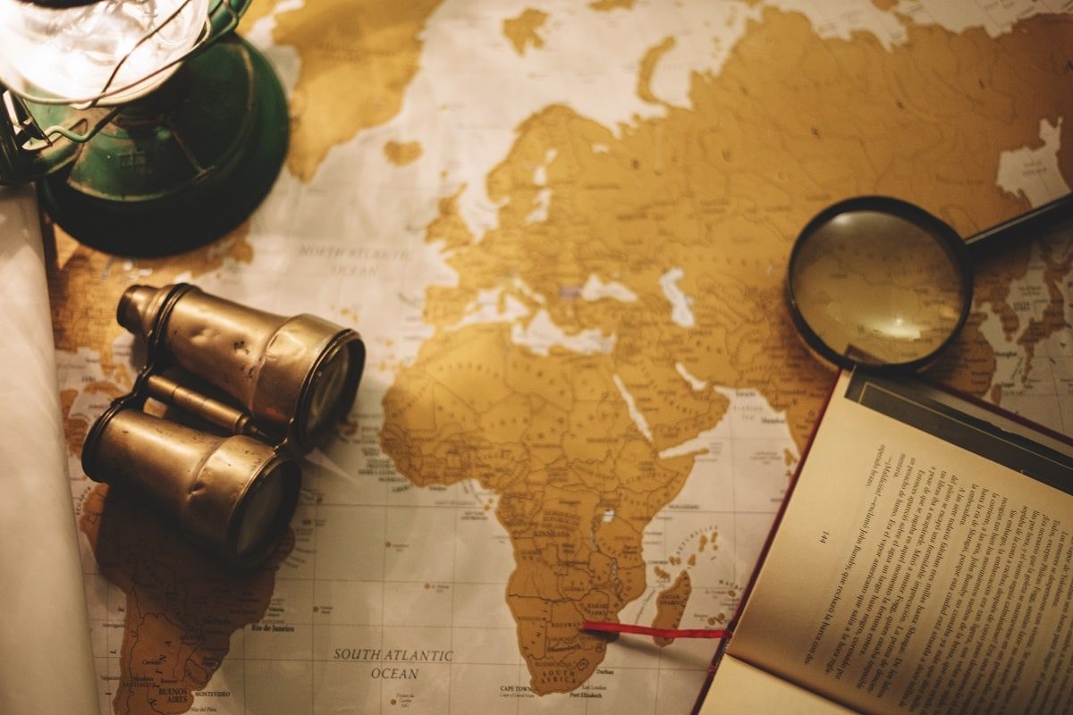 Libros sobre las grandes expediciones y aventuras de la humanidad binoculars and magnifying glass on map