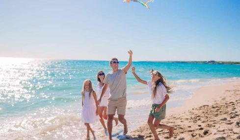 una familia juega con una cometa en la playa
