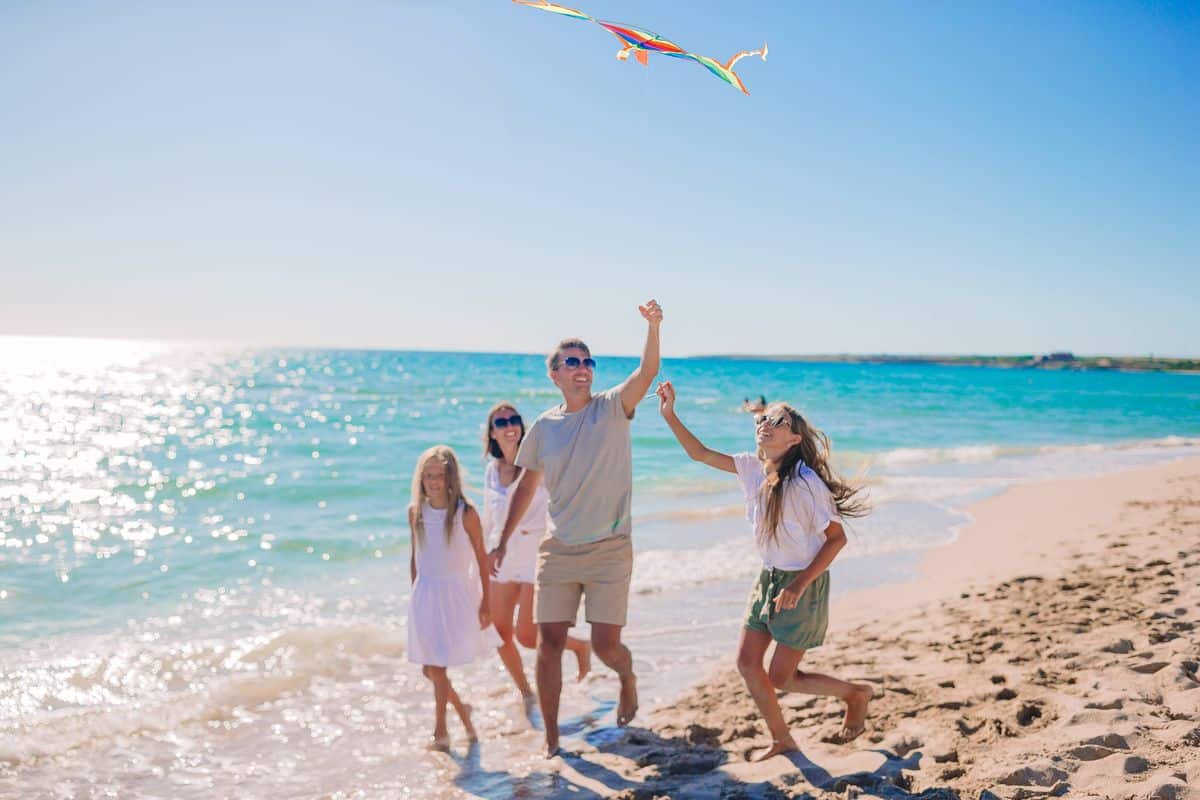 una familia juega con una cometa en la playa