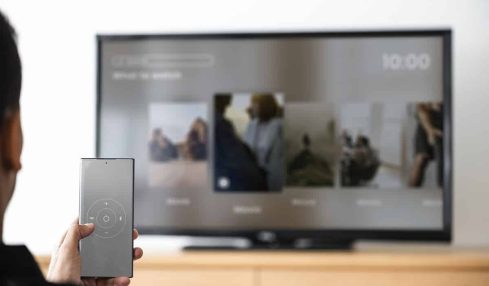 man changing tv channel by his smartphone