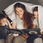 Familia leyendo bajo una sábana