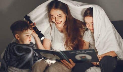 Familia leyendo bajo una sábana