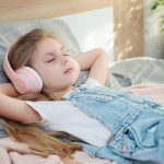Niña tumbada escuchando música relajante.