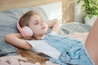 Niña tumbada escuchando música relajante.