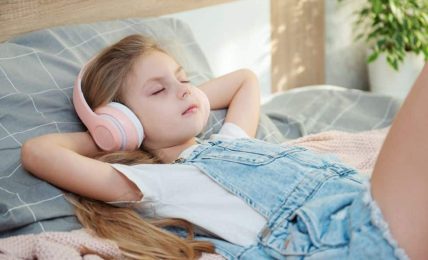 Niña tumbada escuchando música relajante.