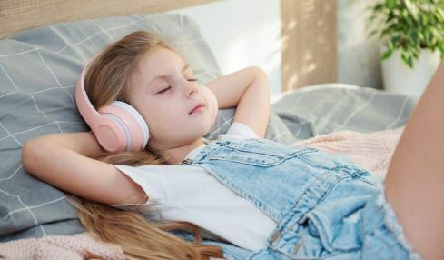 Niña tumbada escuchando música relajante.