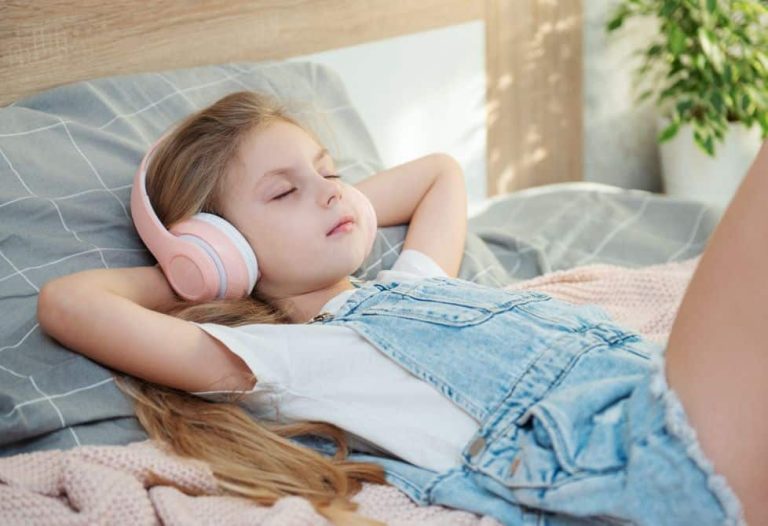 Niña tumbada escuchando música relajante.