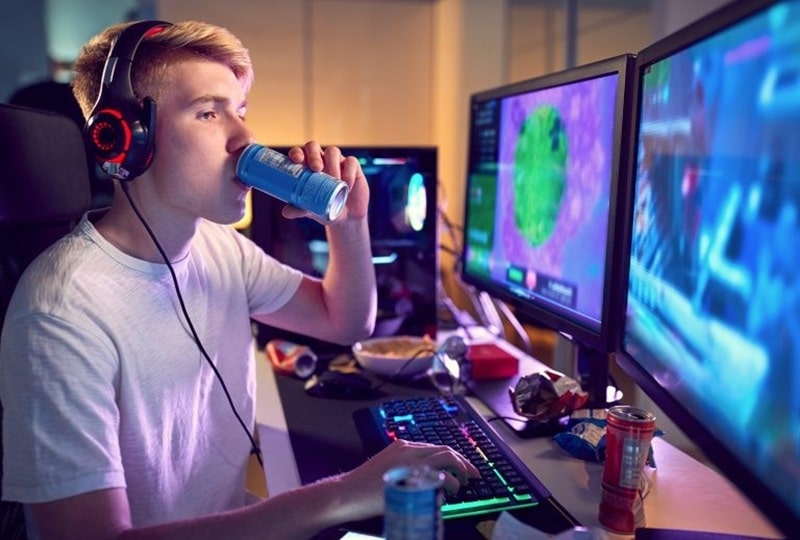 adolescente tomando bebidas energéticas mientras juega a videojuegos 